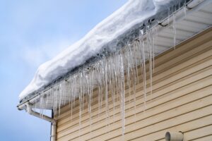 Sharp,Spiked,Icicles,On,Roof,With,Snow,Against,Blue,Sky. Sharp,Spiked,Icicles,On,Roof,With,Snow,Against,Blue,Sky.